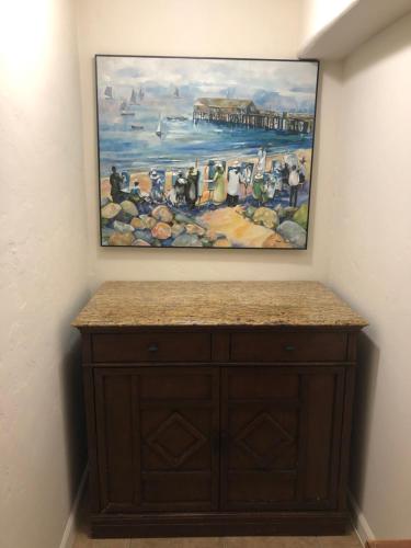 una pintura colgada en una pared sobre un armario de madera en Ala Mar by the Sea, en Santa Bárbara