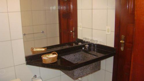 ein Bad mit einem schwarzen Waschbecken und einem Spiegel in der Unterkunft Pousada Casa Dona Rosa in Cumbuco