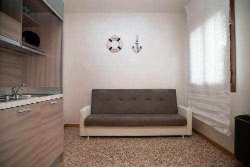 a brown couch in a kitchen with a sink at Green Apartment in Rosolina Mare
