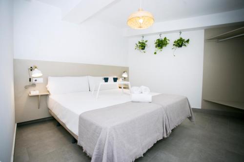 een slaapkamer met een groot wit bed met witte lakens bij MONKÓ - COCO & TROPYCAL APARTMENT o in Torremolinos