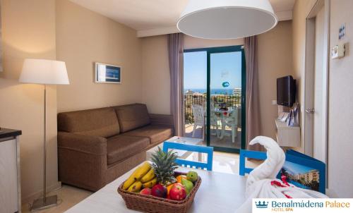 a living room with a table with a basket of fruit at Benalmadena Palace Spa in Benalmádena