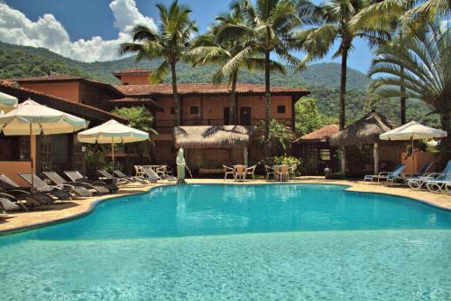 a swimming pool in front of a resort with palm trees at Hotel Pousada dos Condes in Maresias
