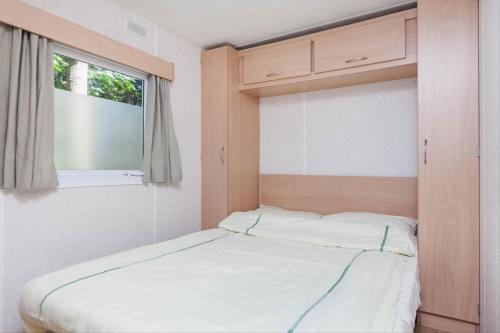 łóżko w pokoju z oknem w obiekcie RA Veluwe Mobile home w Arnhem