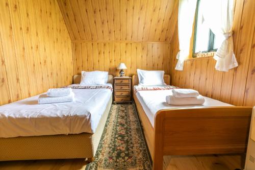 two beds in a room with wood paneling at Guest house Holiday in Žabljak