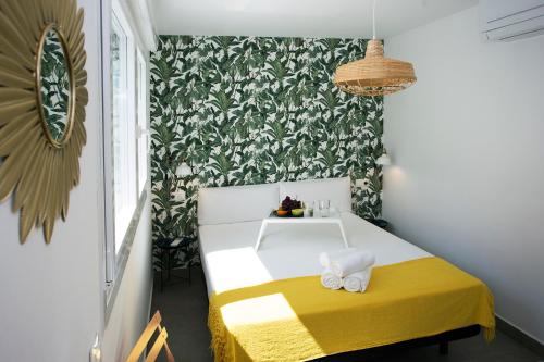 Habitación pequeña con cama blanca y amarilla y pared en MONKÓ - BANANA & TROPYCAL APARTMENT o, en Torremolinos
