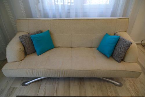 a couch with two blue pillows on it at Central Number 10 in Néa Péramos