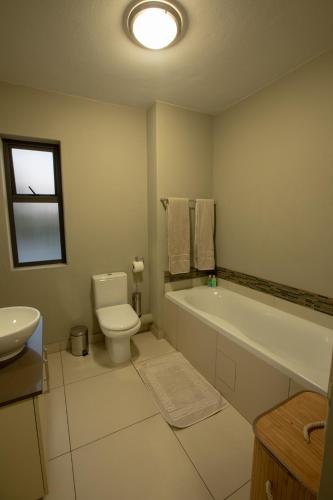 a bathroom with a tub and a toilet and a sink at The Hub Apartments Bryanston in Johannesburg