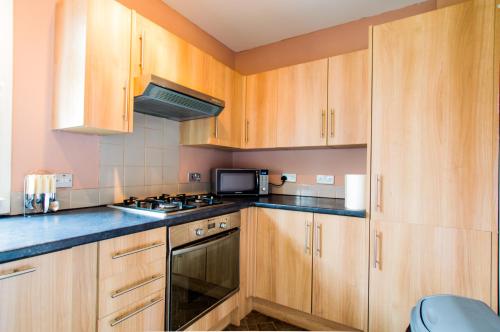 a kitchen with wooden cabinets and a stove top oven at Montgomery Apartments - Stevensons in Edinburgh