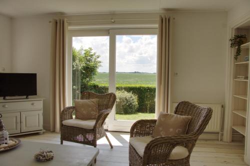 a living room with chairs and a large window at Huisje Linquenda in Moddergat