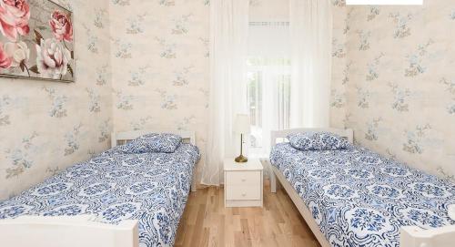 two beds in a bedroom with blue and white wallpaper at Roosi Apartment in Pärnu
