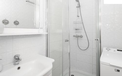 a white bathroom with a shower and a sink at Roosi Apartment in Pärnu
