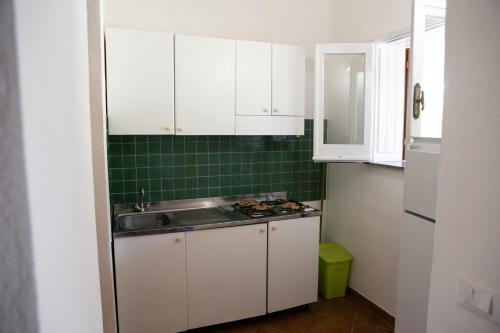 una pequeña cocina con armarios blancos y fregadero en Residenza il Normanno, en Santa Domenica