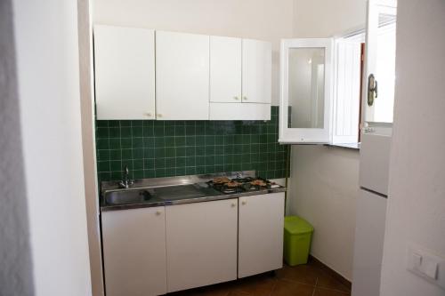 a small kitchen with white cabinets and a sink at Residenza il Normanno - La terrazza sul mare in Santa Domenica