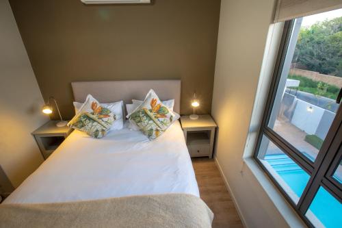 um quarto com uma cama branca com almofadas e uma janela em The Hub Apartments Full Generator Backup em Joanesburgo