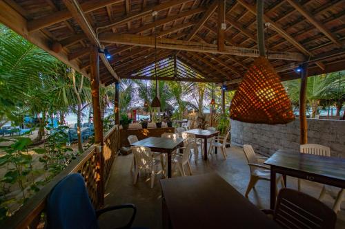 ein Restaurant mit Tischen und Stühlen und einem Kronleuchter in der Unterkunft The Surf Access Guest House in Arugam Bay