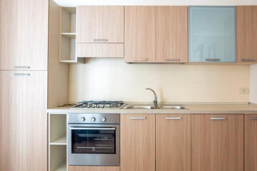 a kitchen with wooden cabinets and a stove and sink at Villa V4 bi-trifamiliare in Isola Albarella