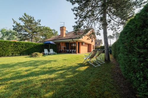 a house with a tree and chairs in the yard at Villa V4 bi-trifamiliare in Isola Albarella