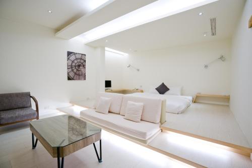 a white living room with a couch and a table at Hotel Shumei Chiayi in Zhongpu