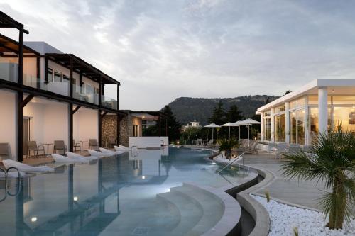 a hotel swimming pool with white chairs and buildings at Nama Retreat in Pastida