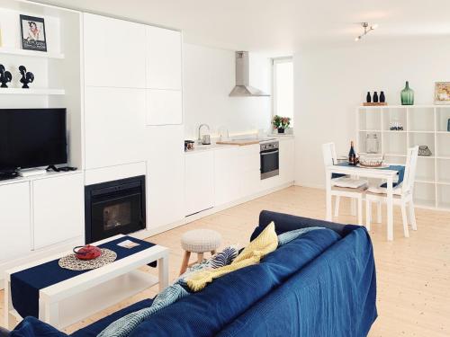 a living room with a blue couch and a kitchen at Modern Beautiful House in Odeceixe