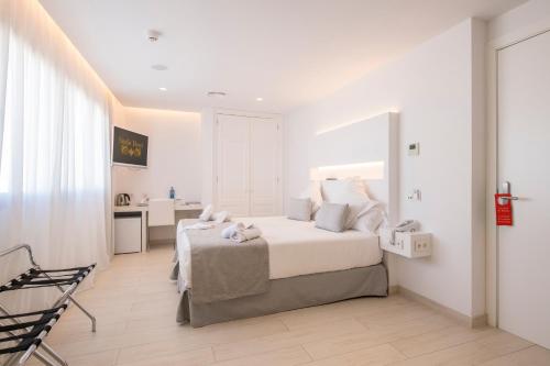 a white bedroom with a bed and a kitchen at Sindic Hotel - Adults Only in Mahón