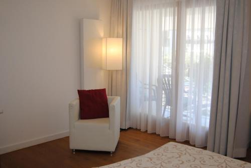 a white chair with a red pillow in a room at Hotel & Restaurant Dankl in Lofer