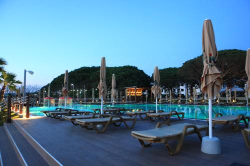 a pool with lounge chairs and umbrellas at night at Hotel GRINT in Golem