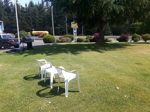 two white chairs sitting in the grass in a park at Fuller Lake Chemainus Motel in Chemainus
