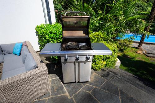 a barbecue grill sitting on a patio next to a couch at Villa delle Palme in Coglio