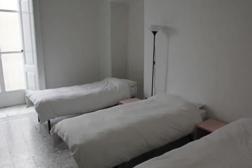 Cette chambre comprend 2 lits avec des draps blancs et une lampe. dans l'établissement Basic 8 Bed Mixed Dorm (share Bathroom), à Naples