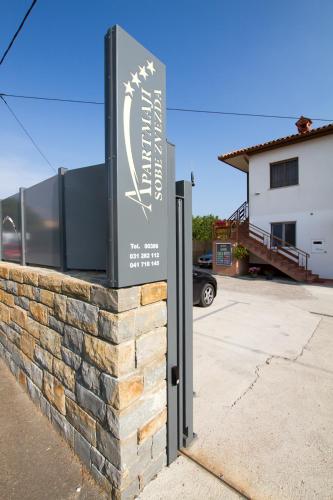 a sign on a brick wall in a parking lot at Apartmaji Sobe Zvezda in Pobegi