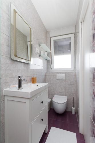 a white bathroom with a sink and a toilet at Apartmaji Sobe Zvezda in Pobegi
