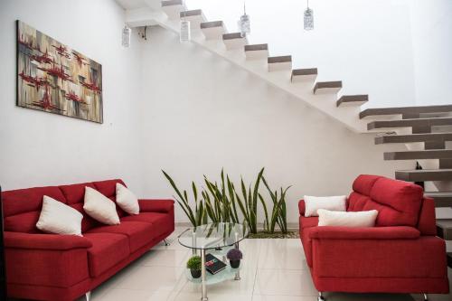 a living room with two red couches and a staircase at Margarett Hotel in Valladolid
