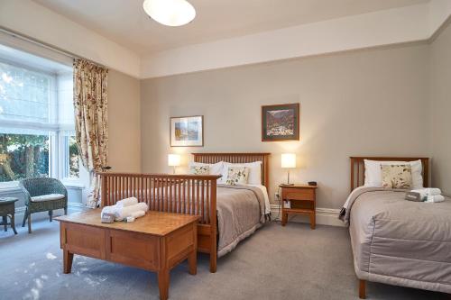 a bedroom with two beds and a table and a window at Orari Boutique Hotel in Christchurch