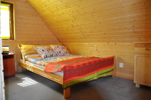 a bed in a log cabin with a wooden ceiling at Sosenka Domki in Odargowo