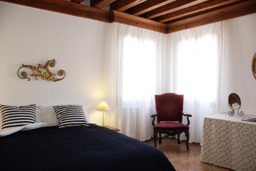 a bedroom with a bed and a chair and windows at Appartamenti San Luca in Venice