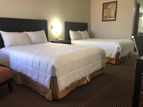 a hotel room with two beds and a chair at Friona Inn in Friona