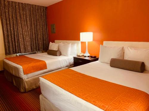 two beds in a hotel room with orange walls at Howard Johnson by Wyndham North Bergen in North Bergen