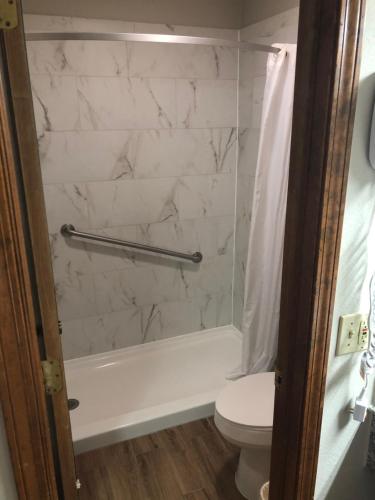 a bathroom with a white tub and a toilet at Friona Inn in Friona