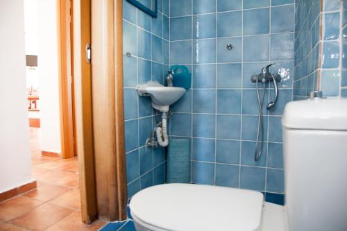 a blue tiled bathroom with a toilet and a shower at Villa Arogi in Aroyí