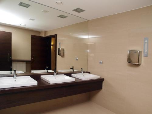 a bathroom with three sinks and a large mirror at Hotel Budweis in České Budějovice