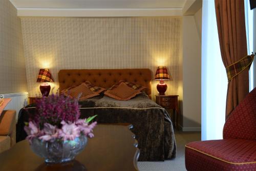 a bedroom with a bed and a table with a vase of flowers at Vila Klasika in Birštonas