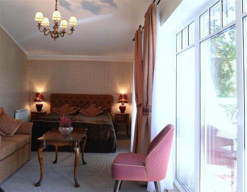 a bedroom with a bed and a table and a chair at Vila Klasika in Birštonas