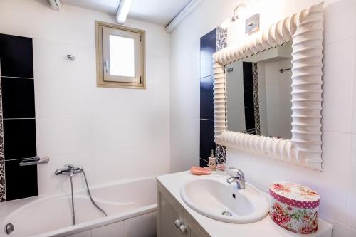 a bathroom with a sink and a tub and a mirror at Kallirroe Master Villa with Sea View and Pool in Chrissi Akti