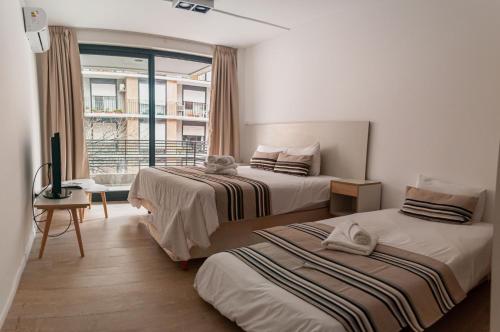 um quarto de hotel com duas camas e uma janela em Babel Alto em Buenos Aires