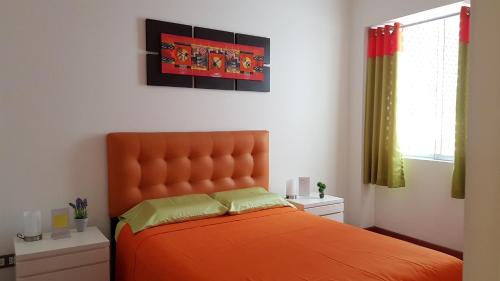 1 dormitorio con cama de color naranja y ventana en Amazing Apartment in Miraflores Larcomar, en Lima