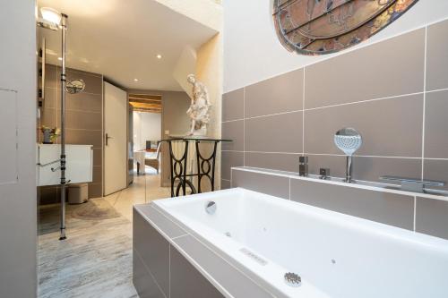 y baño con bañera blanca y espejo. en La maison de Raphaël, en Tournon-sur-Rhône