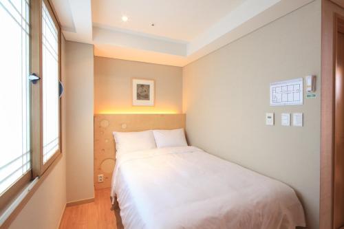 a small bedroom with a white bed and a window at Dream House in Seoul
