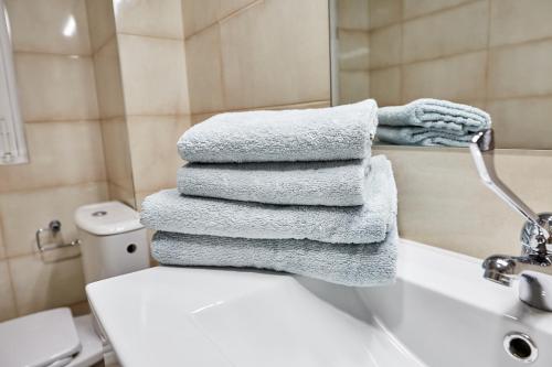 - une pile de serviettes assises au-dessus des toilettes dans la salle de bains dans l'établissement New Apartment Explanada, à Alicante