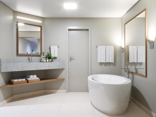 a white bathroom with a tub and a sink at Café Palace Hotel in Três Pontas